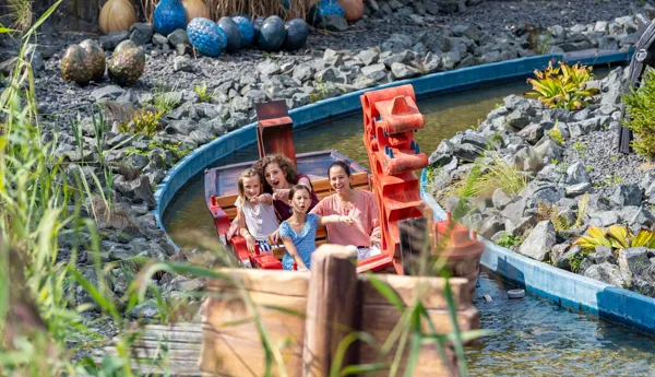 Zwei Frauen und zwei Mädchen sitzen im Wikingerboot und erkunden die Attraktion "Drachengrotte" im Heide Park Resort.